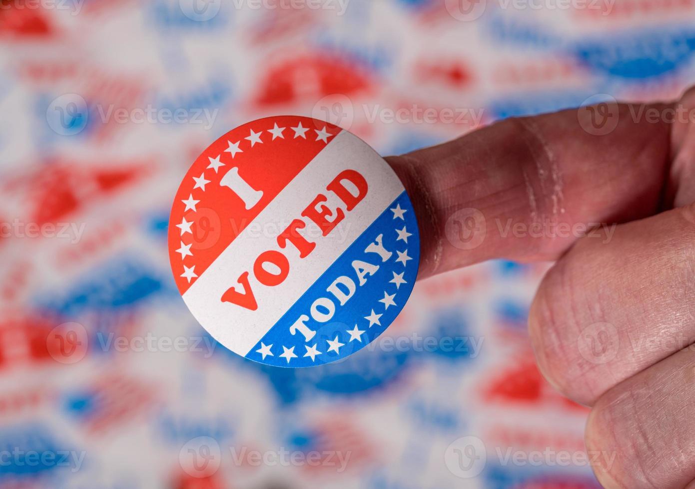 Finger mit dem Aufkleber „Ich habe heute gewählt“ vor dem Hintergrund, der aus vielen Wahlabzeichen erstellt wurde foto