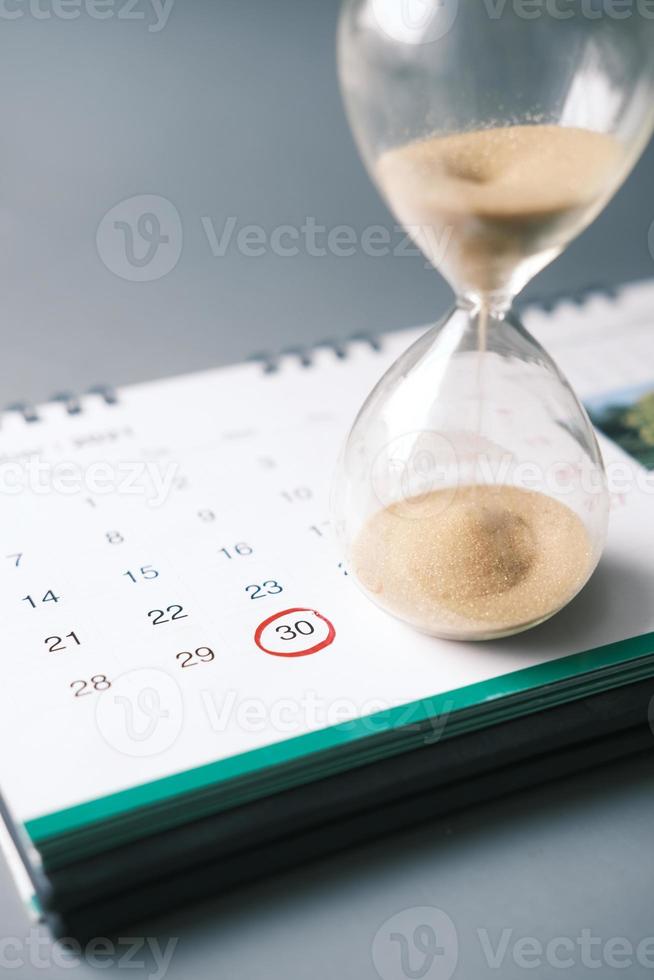 Sanduhr auf einem Kalender und fließt durch die Sanduhrkugel foto