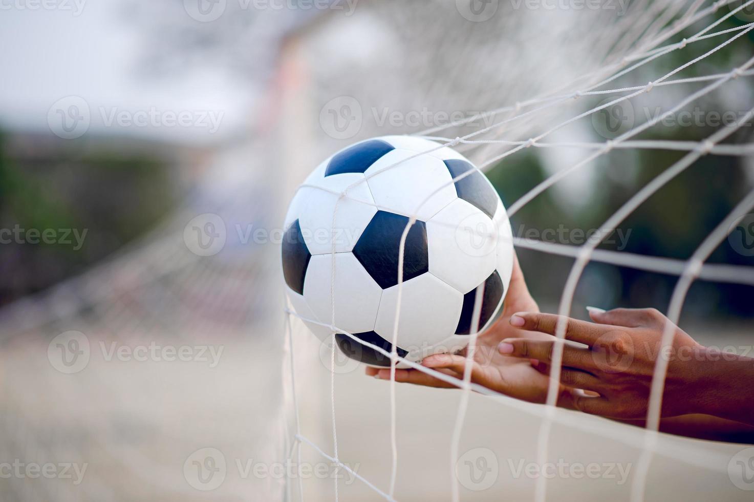 das zugeschnittene Bild von Sportlern, die den Ball und das Fußballfeld fangen. Sport-Image-Konzept. foto