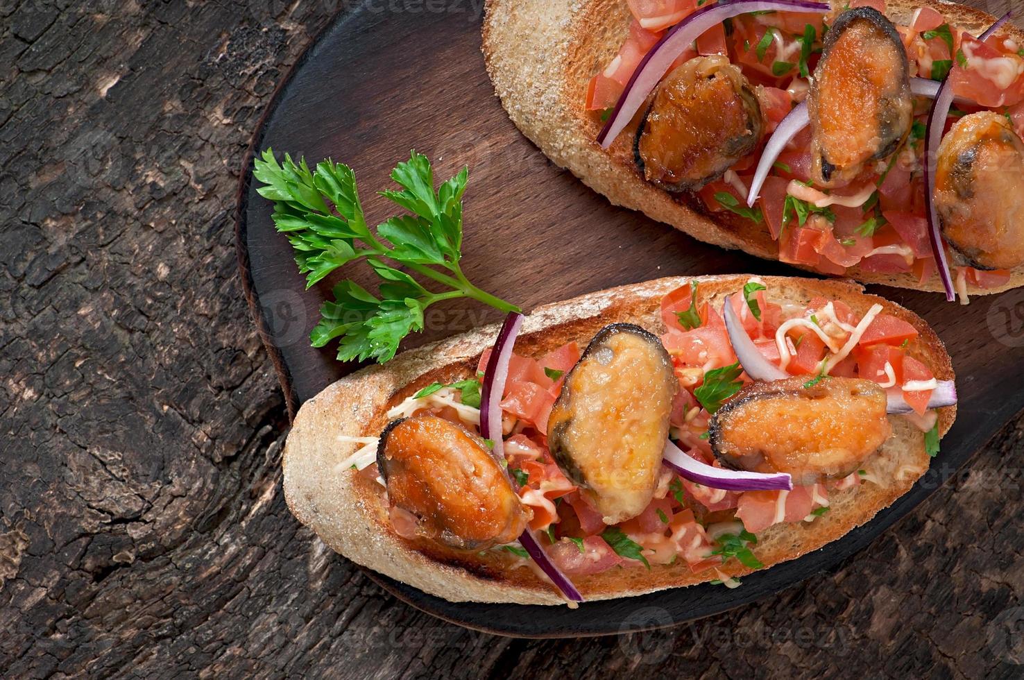 Bruschetta mit Muscheln, Käse und Tomaten foto