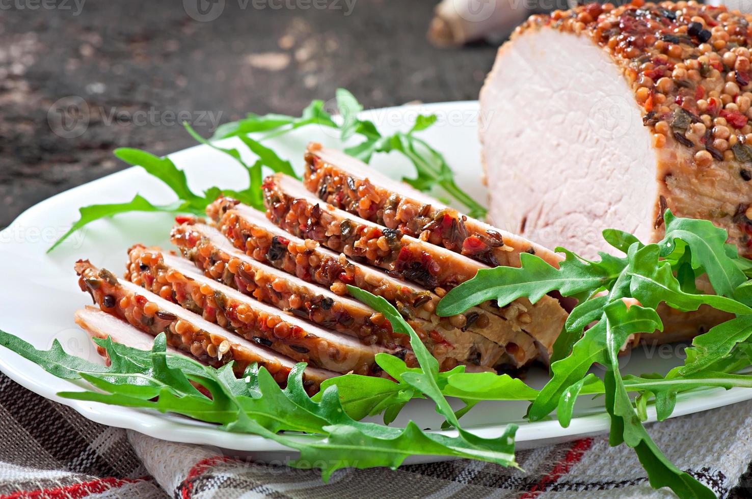 Gebackenes Schweinefleisch, dekoriert mit Rucolablättern foto