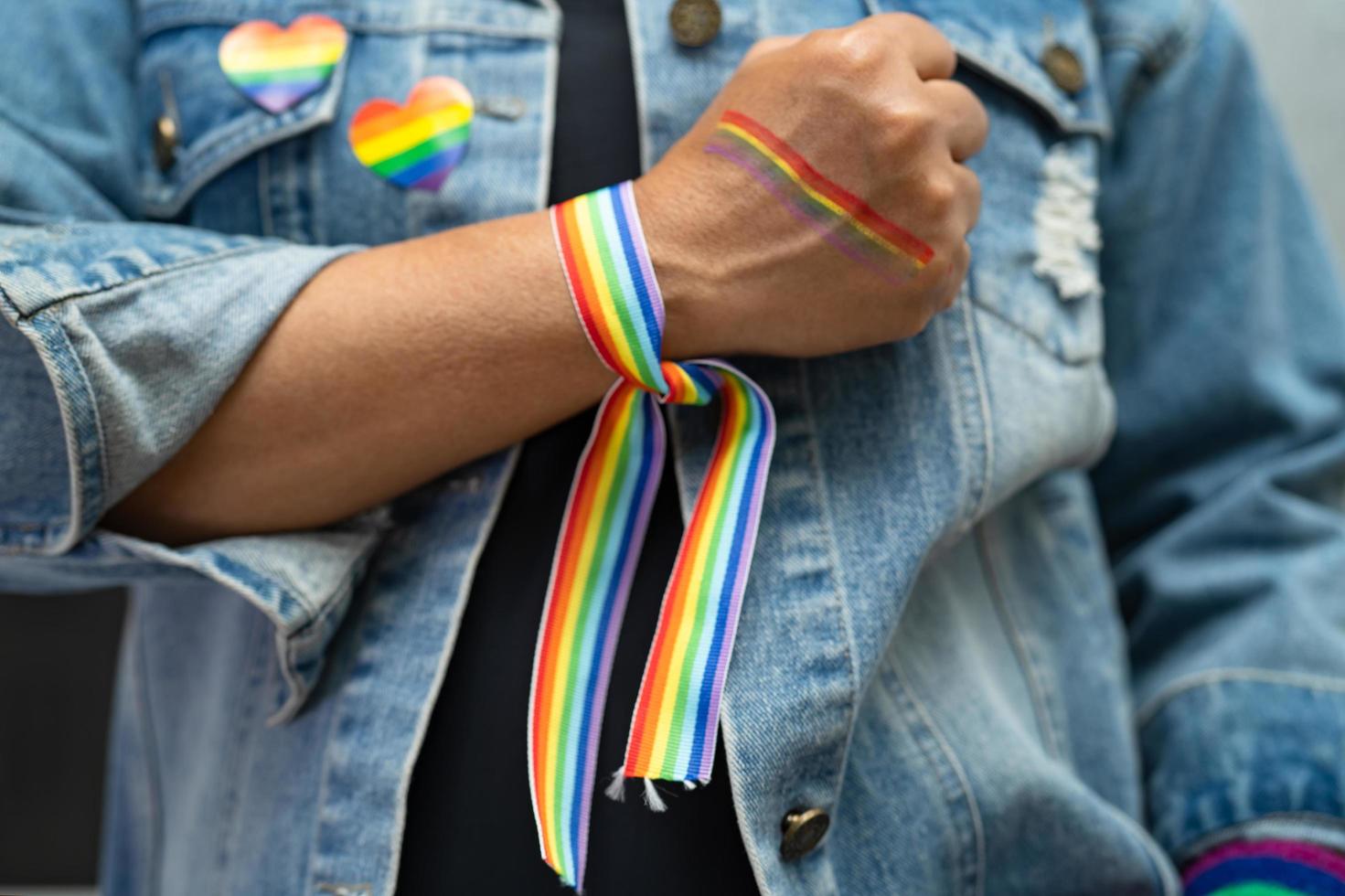 asiatische dame mit regenbogenflaggenarmbändern, symbol des lgbt-stolzmonats, feiert jährlich im juni die sozialarbeit von schwulen, lesbischen, bisexuellen, transgendern und menschenrechten. foto