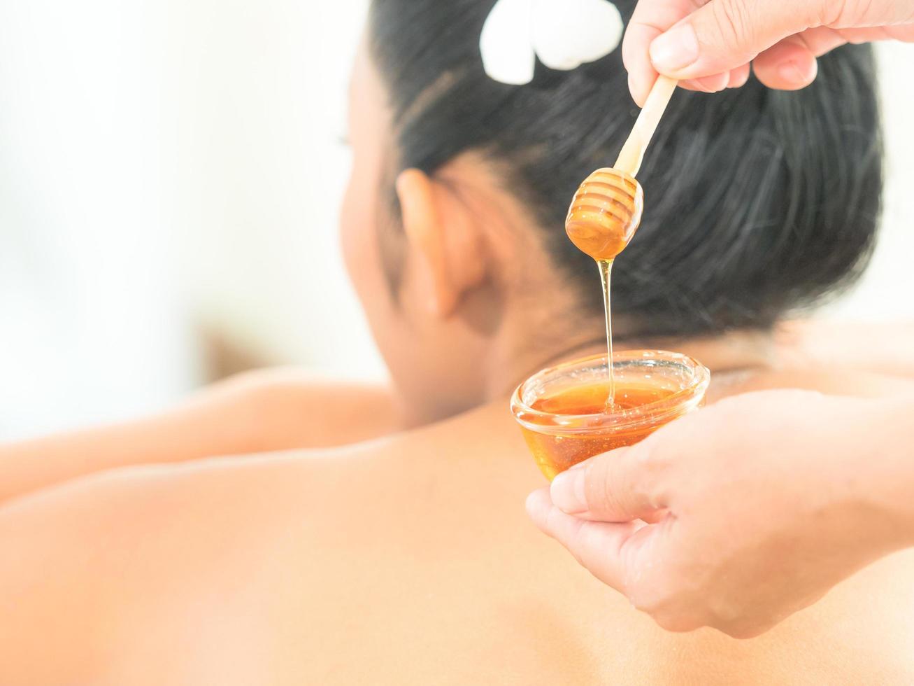junge asiatische schöne frau, die sich mit hautpflege von honig im spa-salon entspannt foto