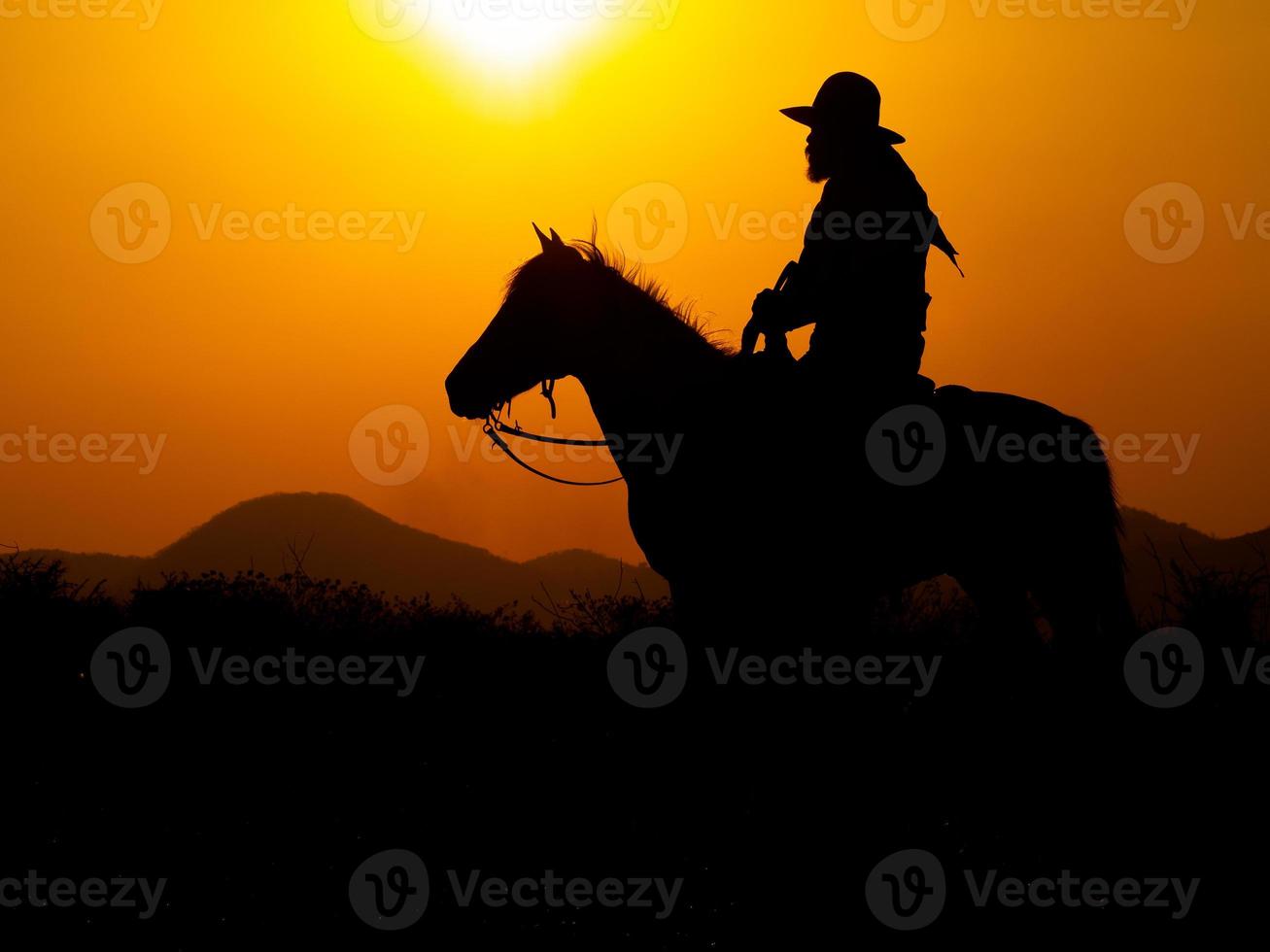 westliche Cowboys sitzen auf Pferden unter der Sonne und bereiten sich darauf vor, Waffen einzusetzen, um sich in einem Land zu schützen, das noch nicht legal ist foto