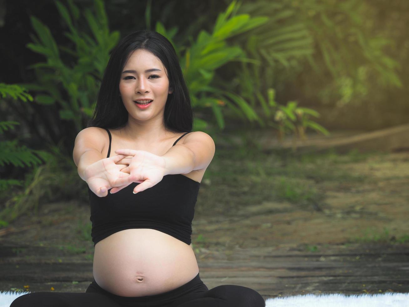Schöne schwangere Frauen sitzen im Park und entspannen sich bei Bewegung für eine gute Gesundheit foto