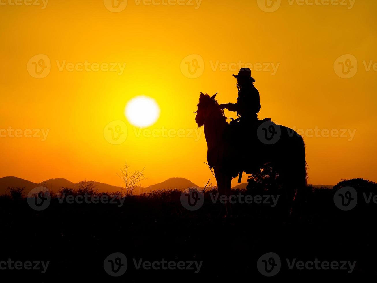 westliche Cowboys sitzen auf Pferden unter der Sonne und bereiten sich darauf vor, Waffen einzusetzen, um sich in einem Land zu schützen, das noch nicht legal ist foto