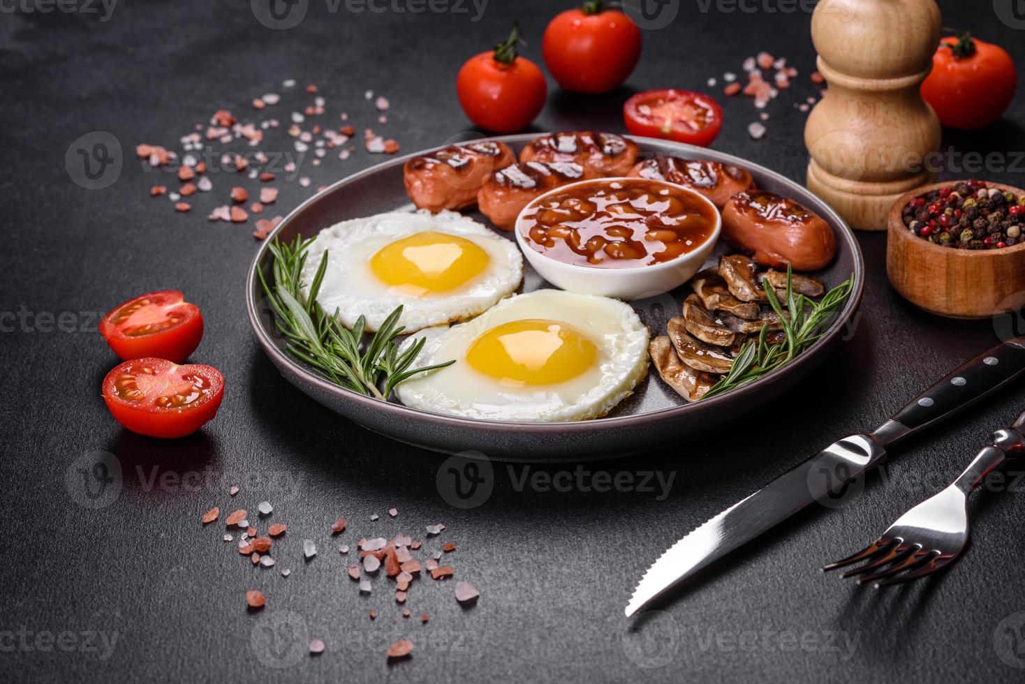 komplettes englisches frühstück mit bohnen, spiegeleiern, gebratenen würsten, tomaten und pilzen foto