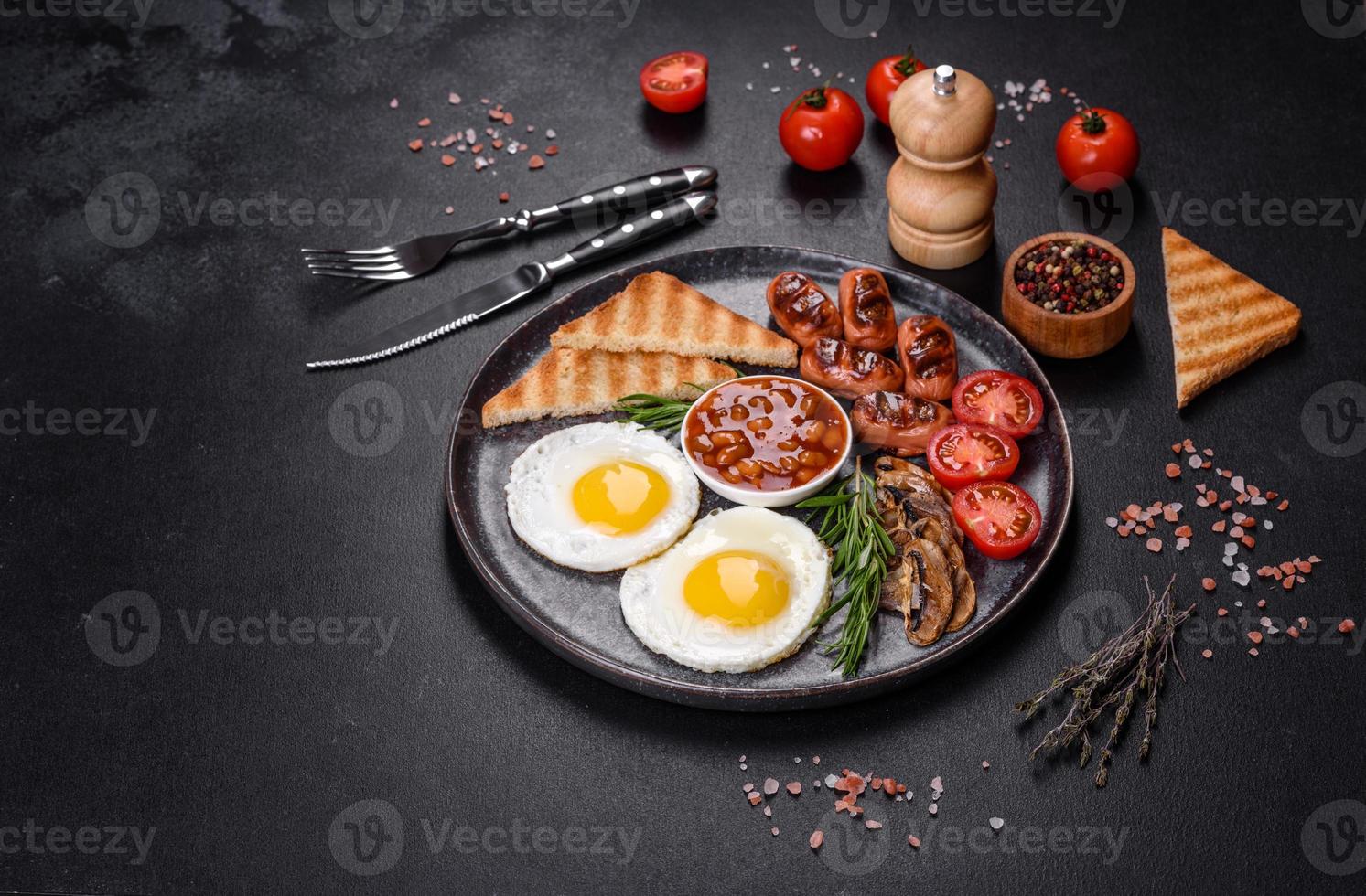 komplettes englisches frühstück mit bohnen, spiegeleiern, gebratenen würsten, tomaten und pilzen foto