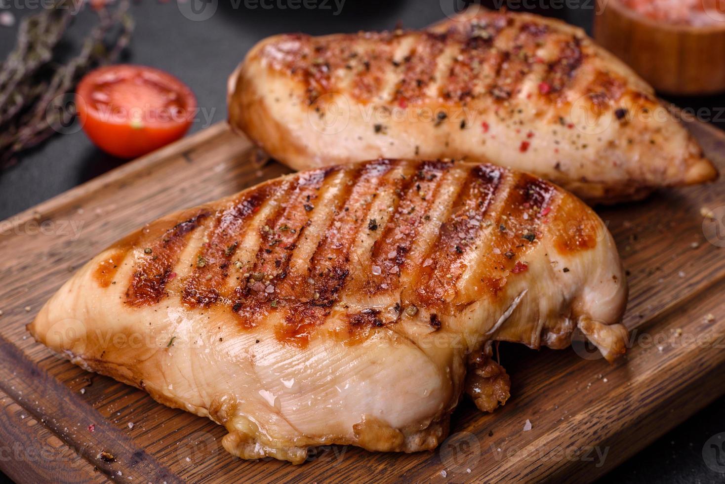 Köstliches frisch gegrilltes Hähnchenfilet mit Gewürzen und Kräutern auf dunklem Betonhintergrund foto