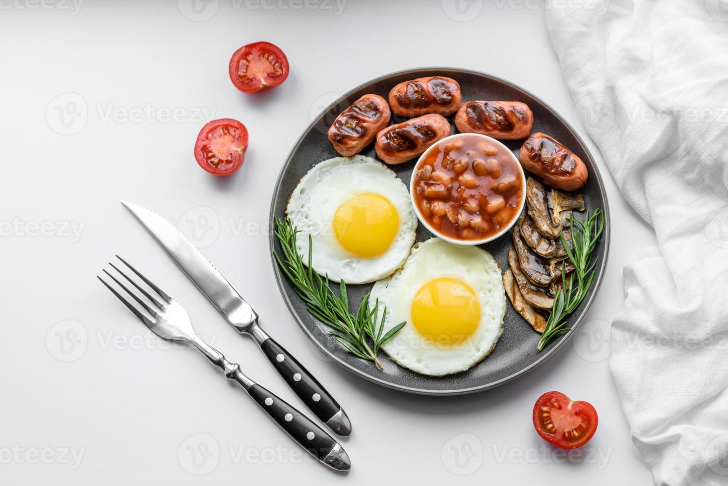 komplettes englisches frühstück mit bohnen, spiegeleiern, gebratenen würsten, tomaten und pilzen foto