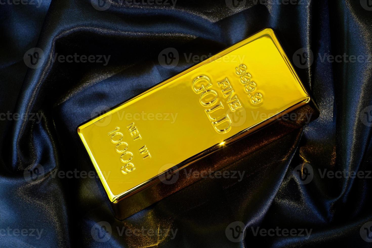 Goldbarren 1 kg auf glattem, elegantem schwarzem Seidenstoff-Luxus-Stoff-Hintergrund foto