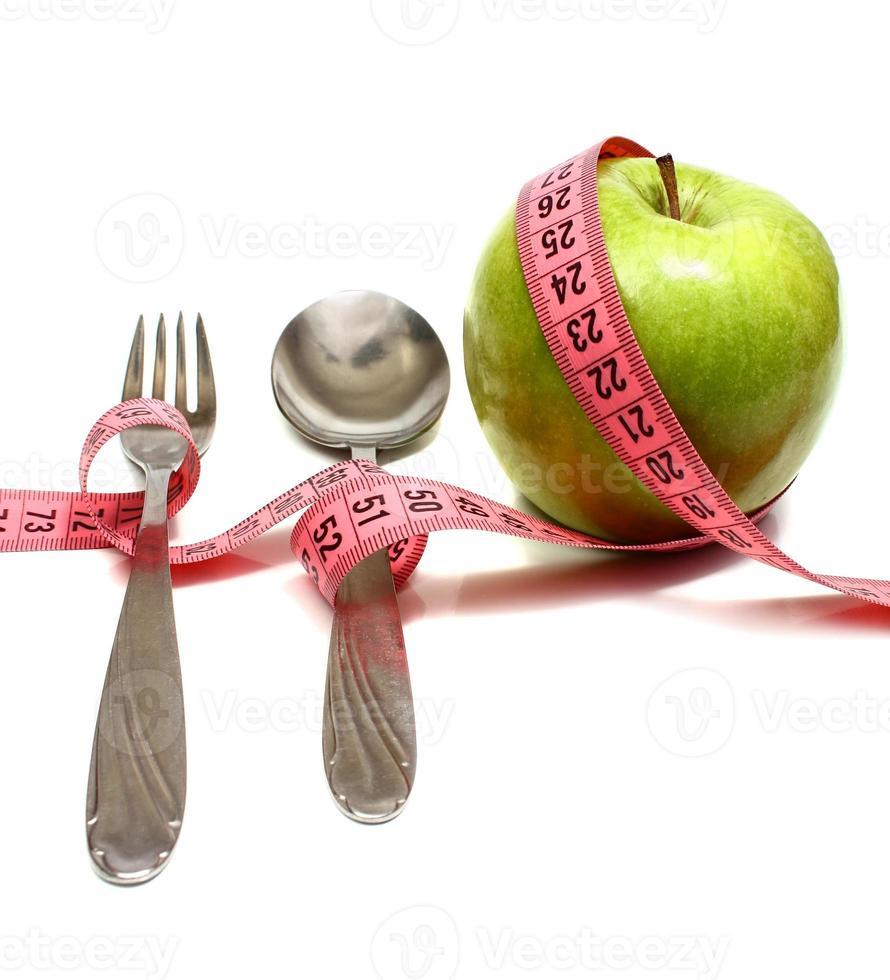Löffelgabel und Apfel werden von einem Band zum Messen der Ernährung aufgereiht foto
