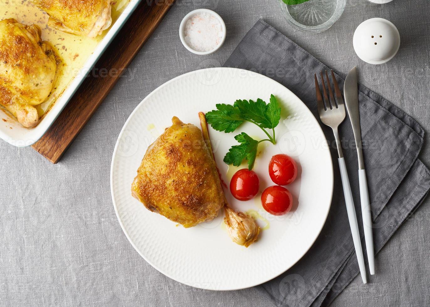 Hähnchenschenkel gebacken mit Kurkuma, Tomaten und Knoblauch. Brathähnchen ist auf dem Teller foto