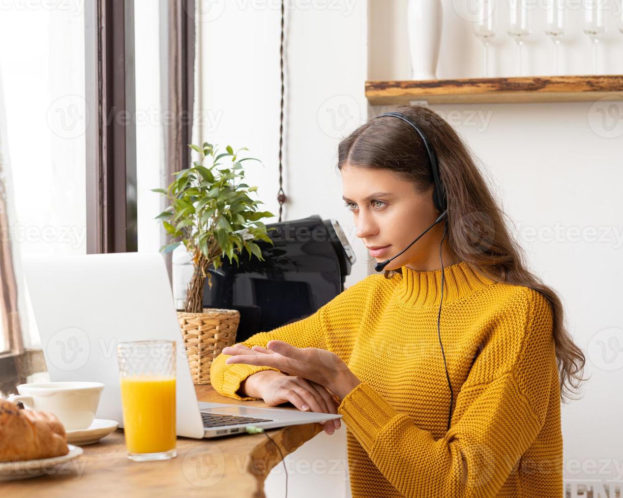 glückliche frau im headset, die per konferenz und video-chat auf dem laptop im büro spricht foto