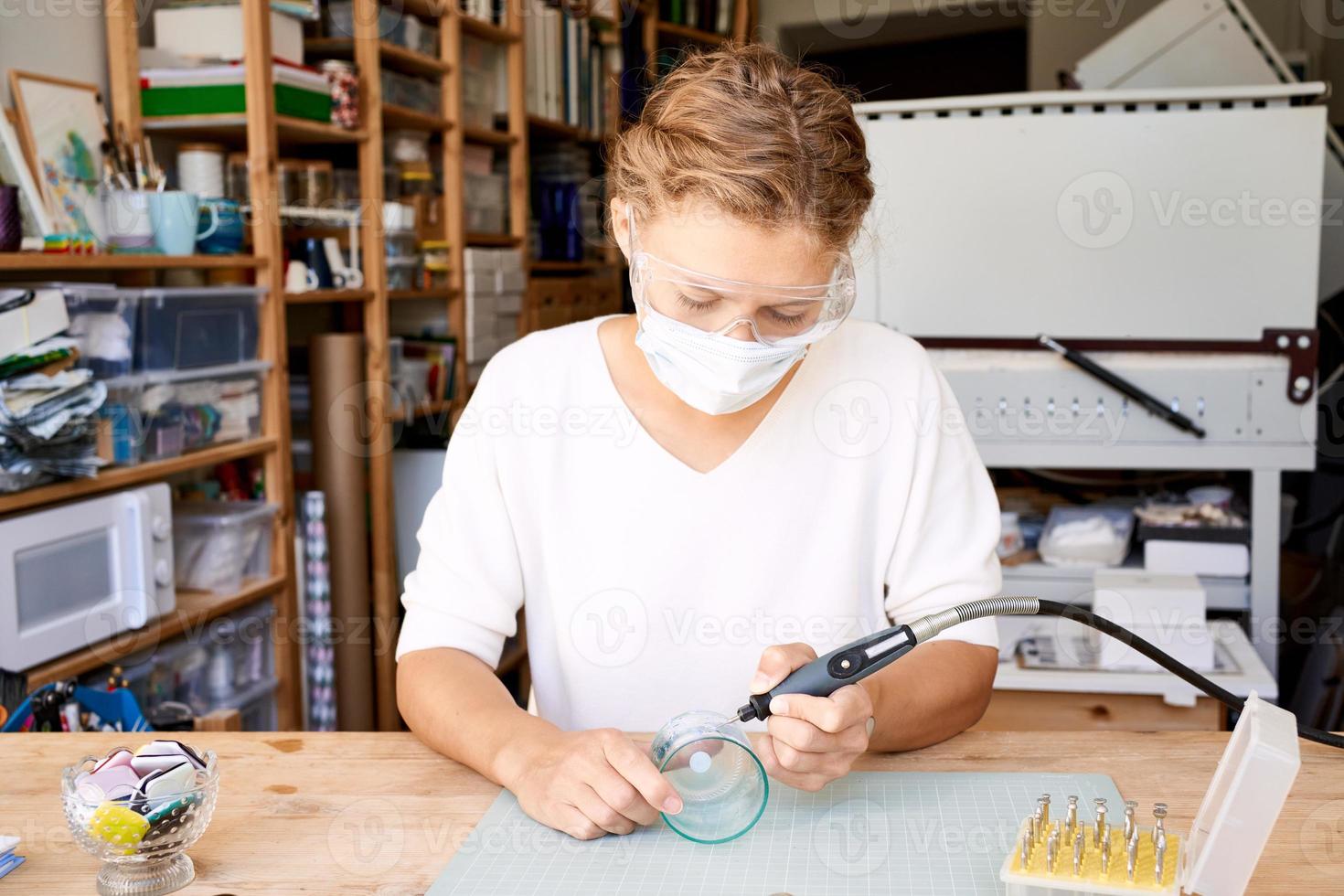 Unternehmerin in Gesichtsschutzmaske Brennglas im handwerklichen Arbeitsraum. Geschäftsfrau foto