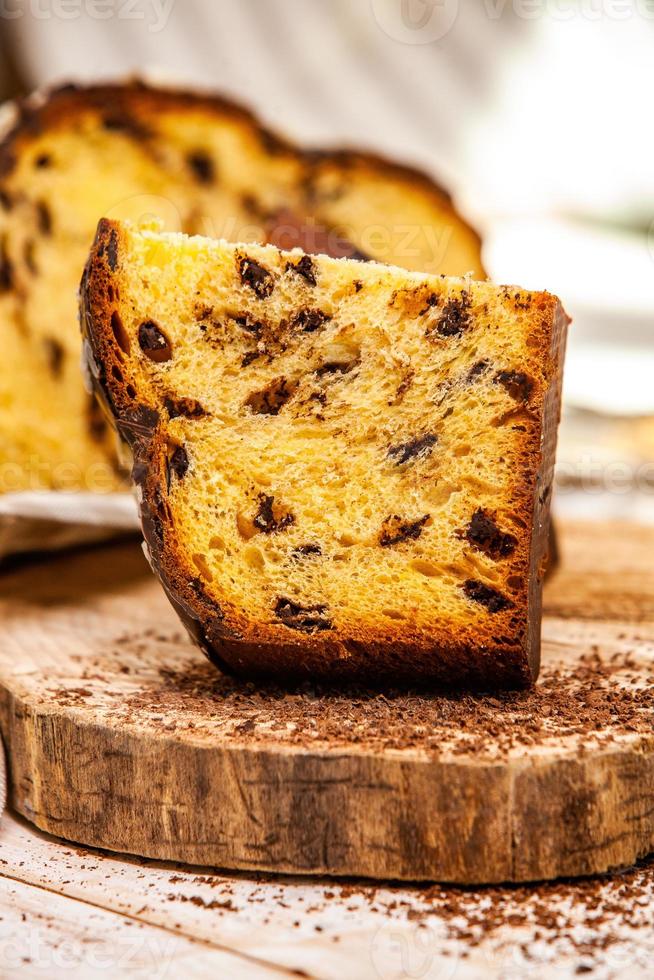 Panettone selbst gemacht. traditionelles italienisches süßes Brot. Panettone mit einer Scheibe serviert auf einem Holztisch. foto