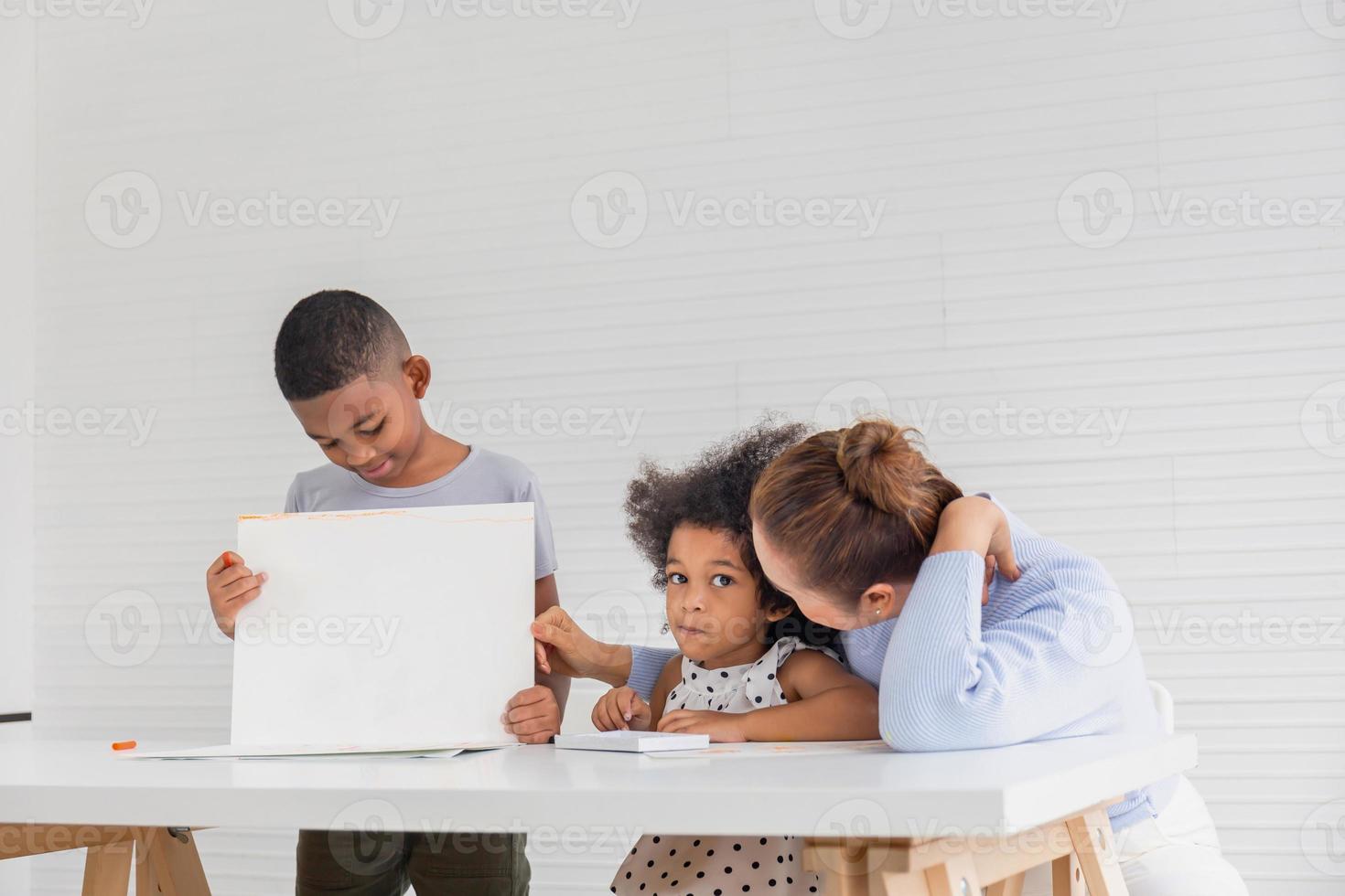 großmutter und enkel spielen fröhlich im wohnzimmer, kinder und großeltern malen zusammen bilder, junge zeigt sein bild foto