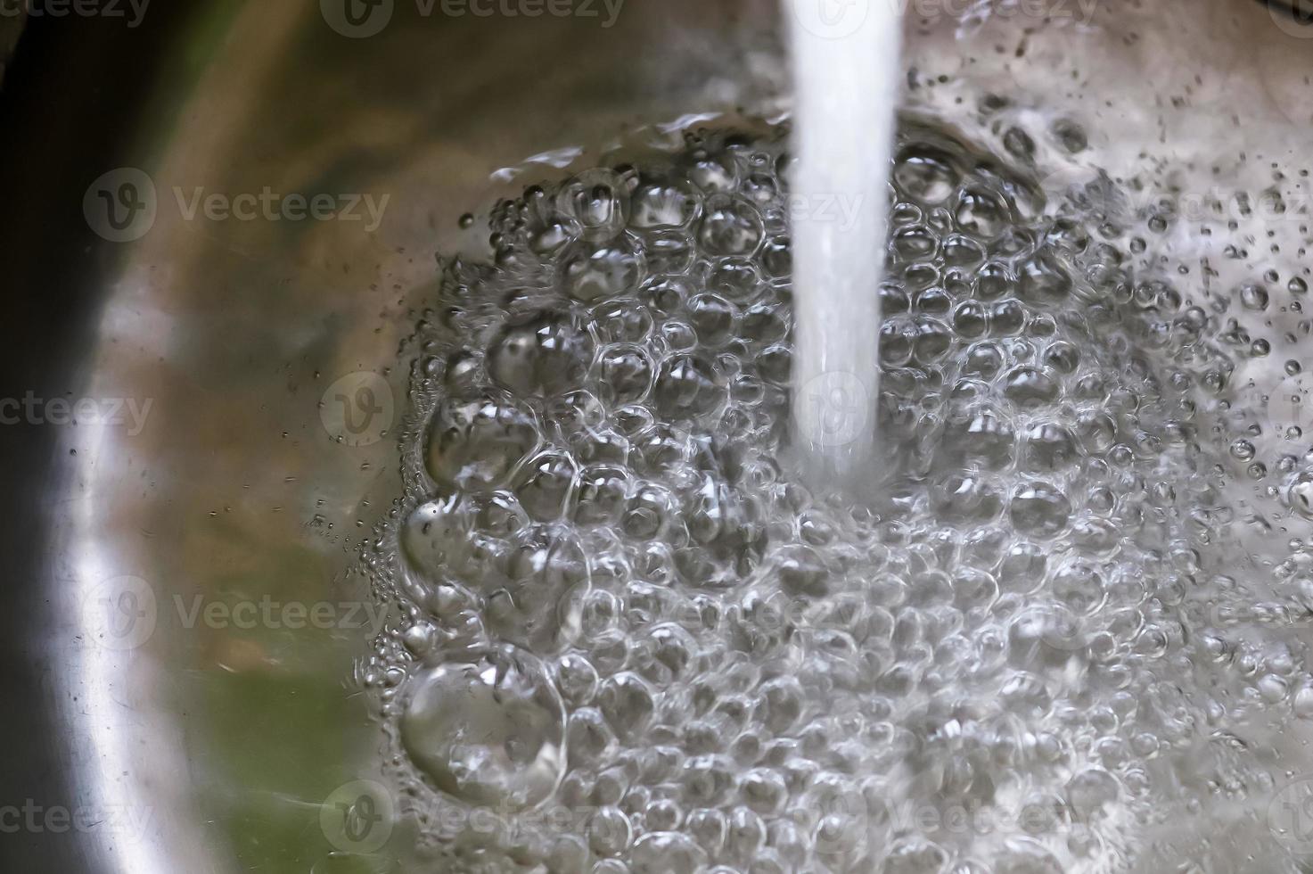 Fließendes Wasser aus einem Wasserhahn in den Abfluss eines verchromten Waschbeckens. foto