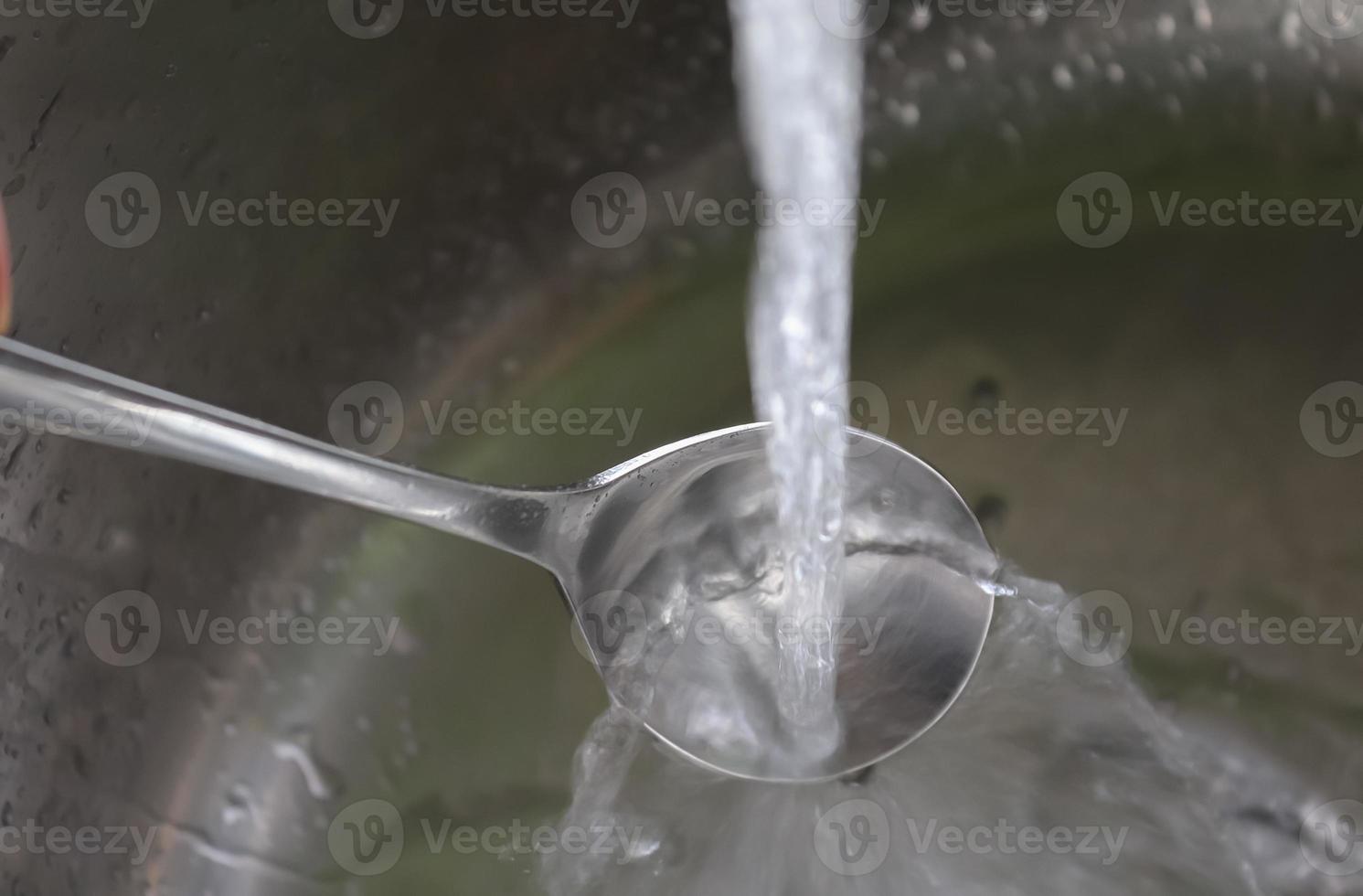 Fließendes Wasser aus einem Wasserhahn in den Abfluss eines verchromten Waschbeckens. foto