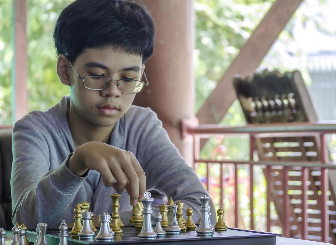 konzentrierter ernster junge, der schachgambit entwickelt, strategie, brettspiel zum gewinner spielt. lern-, taktik- und analysekonzept. foto