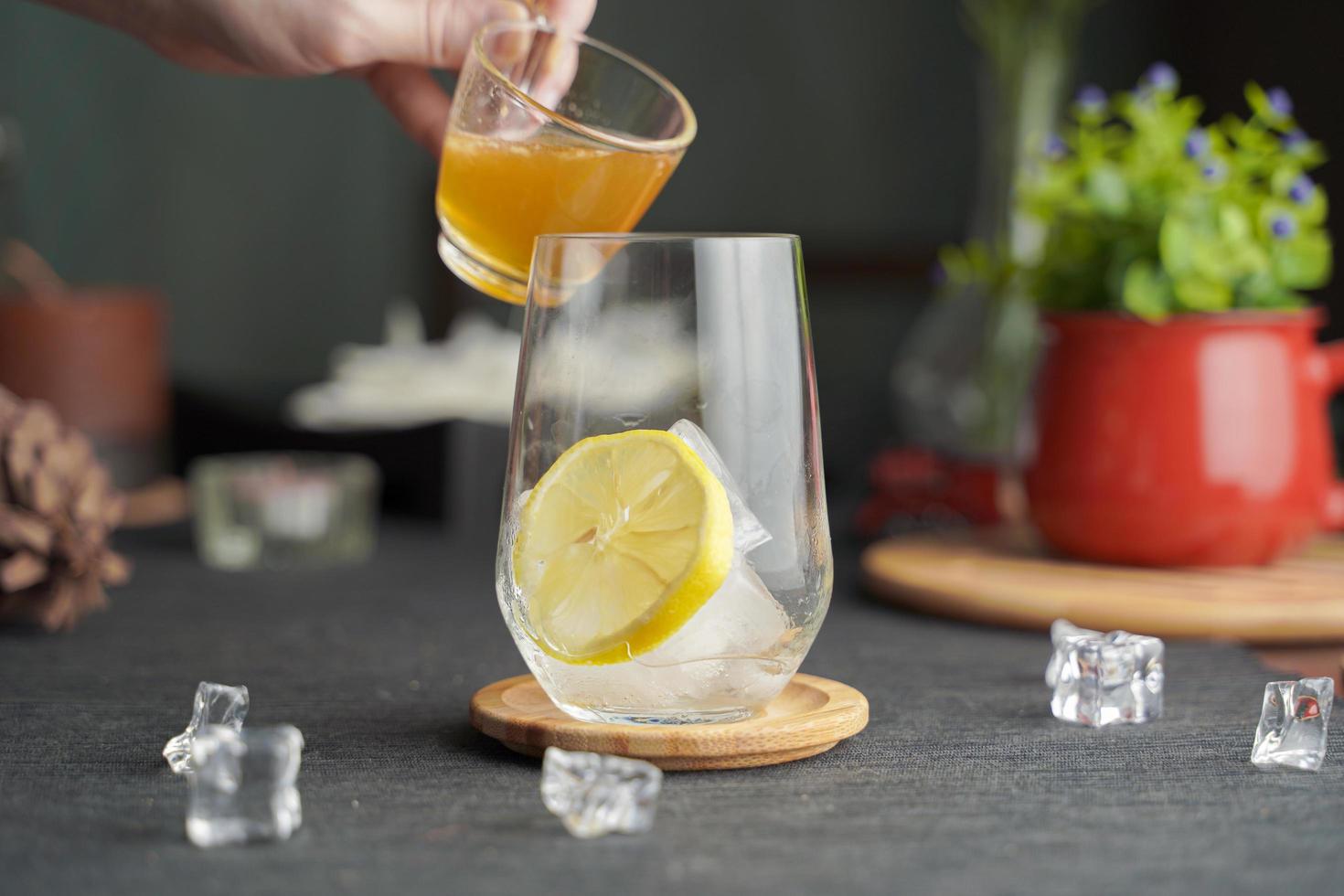 glas espresso mit zitronensaft und frisch geschnittener zitrone auf holztisch und kopierraum, sommercocktail, kaltgebrühter kaffee oder schwarzer tee. kaltes Getränk einschenken. foto