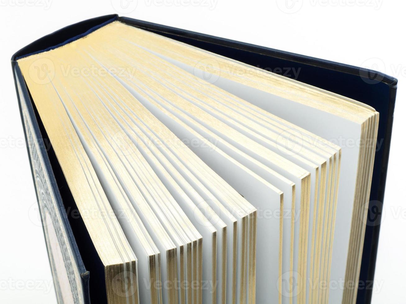 Dickes Buch mit vergoldeten Seiten auf weißem Hintergrund foto