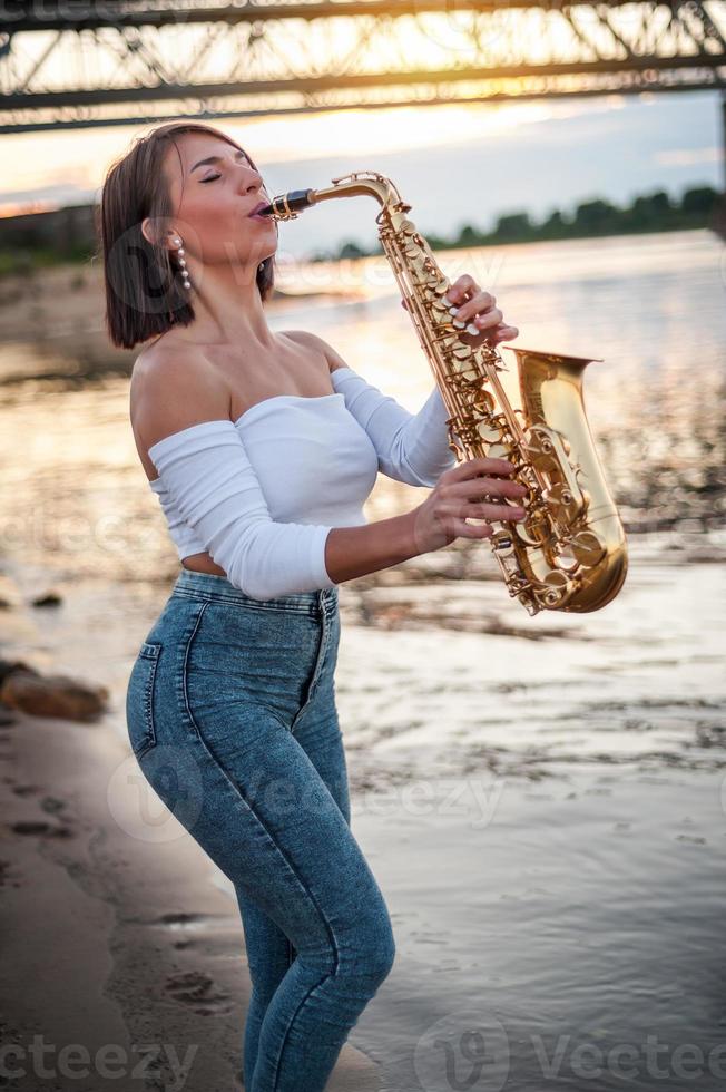 Frau spielt Saxophon bei Sonnenuntergang foto