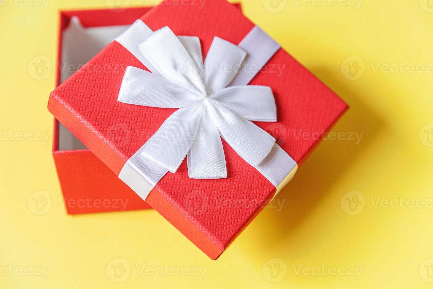 weihnachten neujahr geburtstag valentinstag feier vorhanden romantisches konzept. einfach minimalistisches Design rote Geschenkbox isoliert auf gelbem, farbigem Hintergrund. flach liegend draufsicht kopierraum. foto