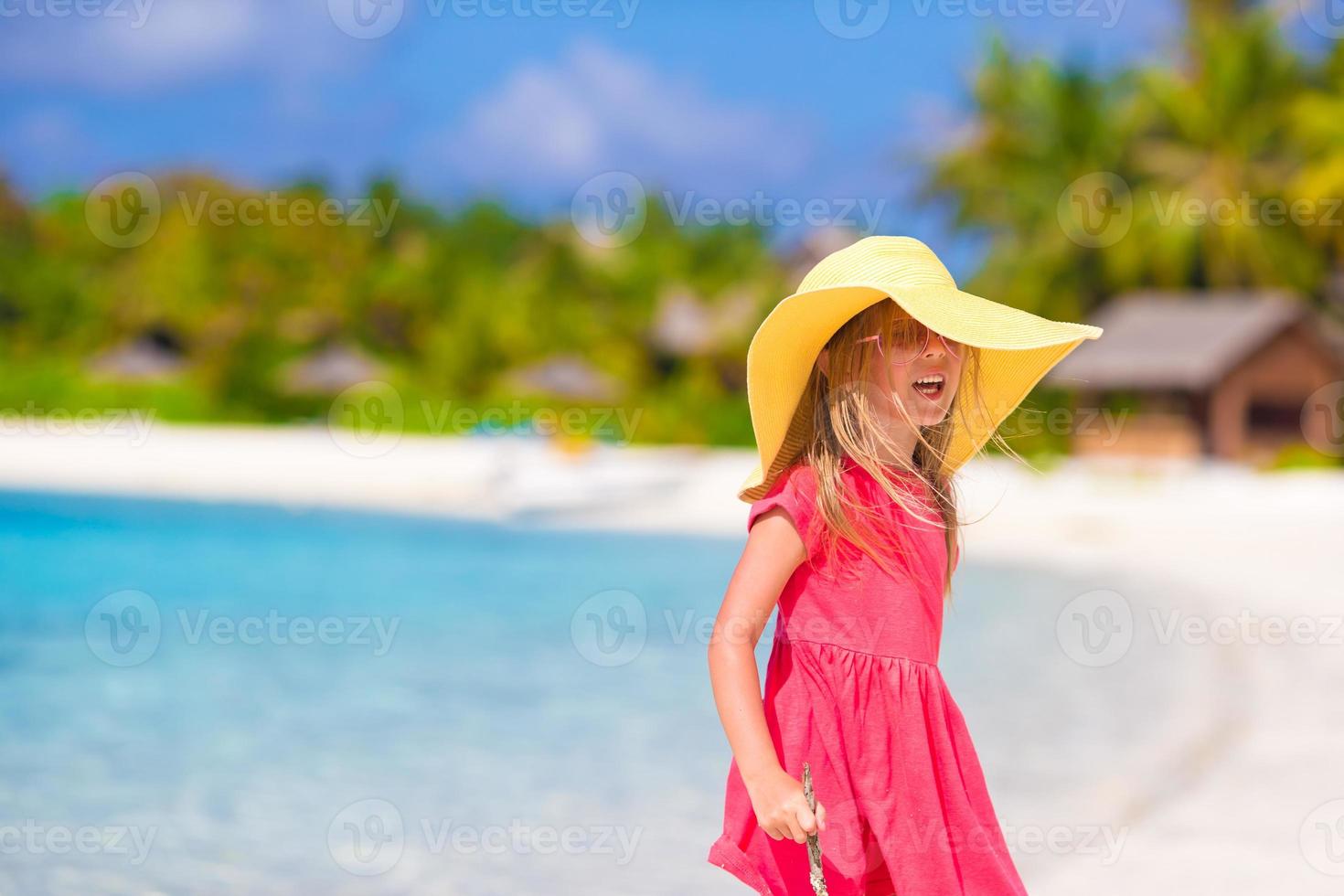 Entzückendes kleines Mädchen mit Hut am Strand während der Sommerferien foto