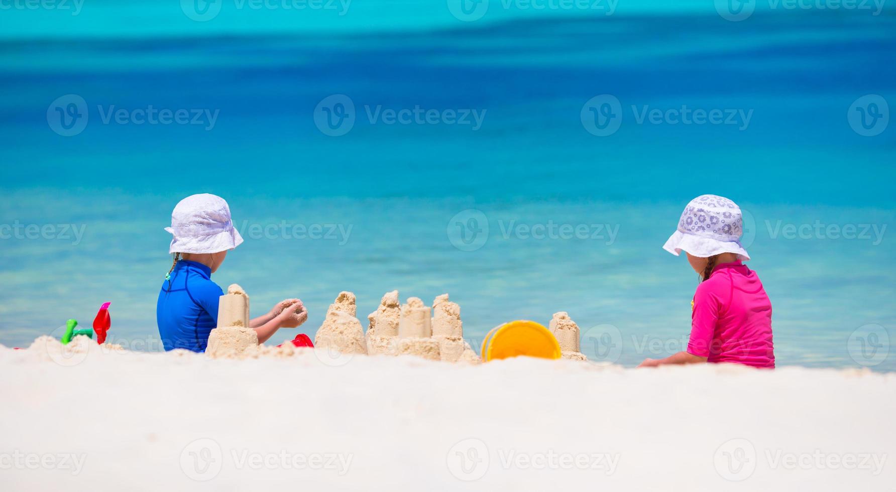 Kleine Mädchen, die während des tropischen Urlaubs mit Strandspielzeug spielen foto