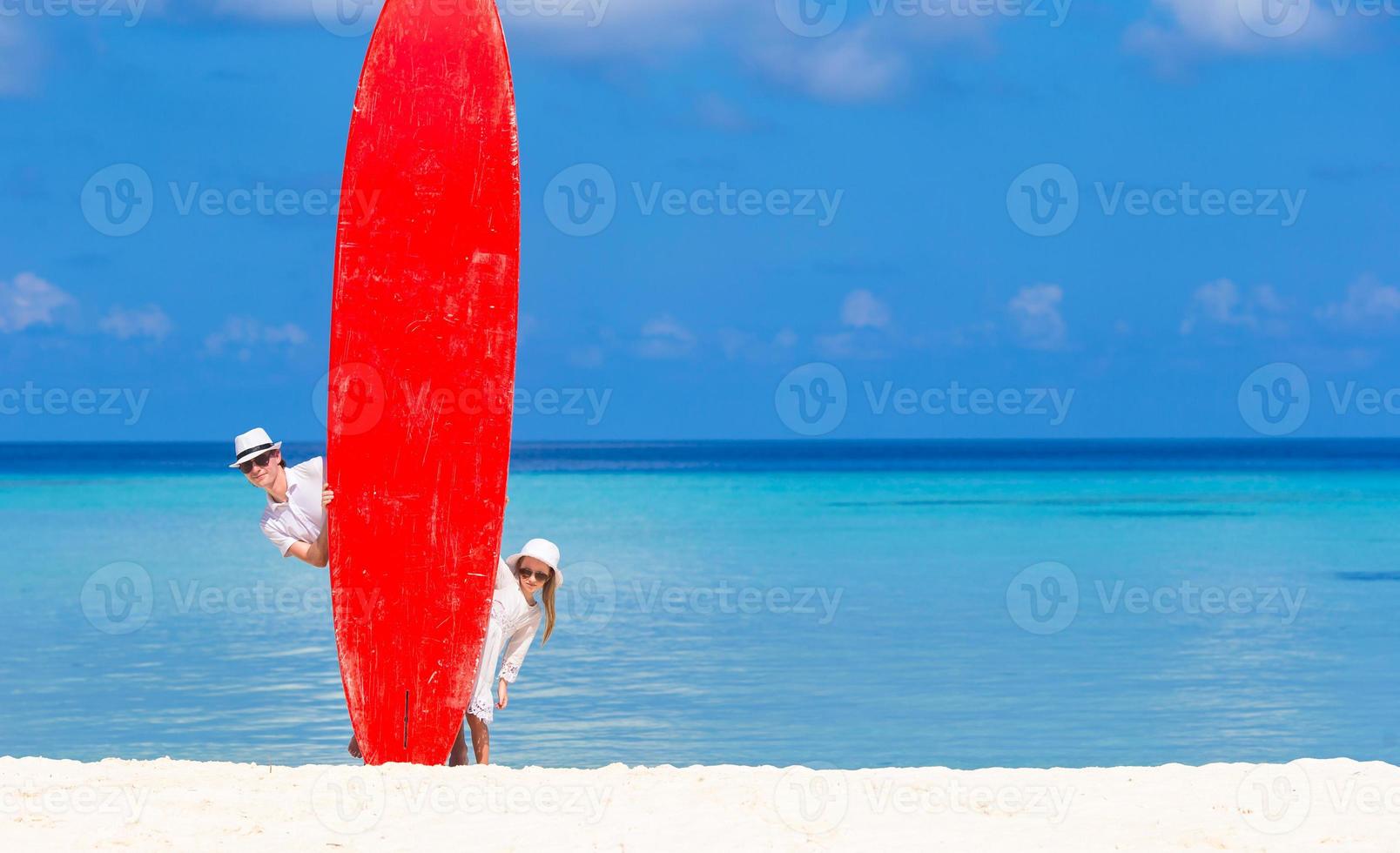 Vater und sein Kind mit Surfbrett in den Sommerferien foto