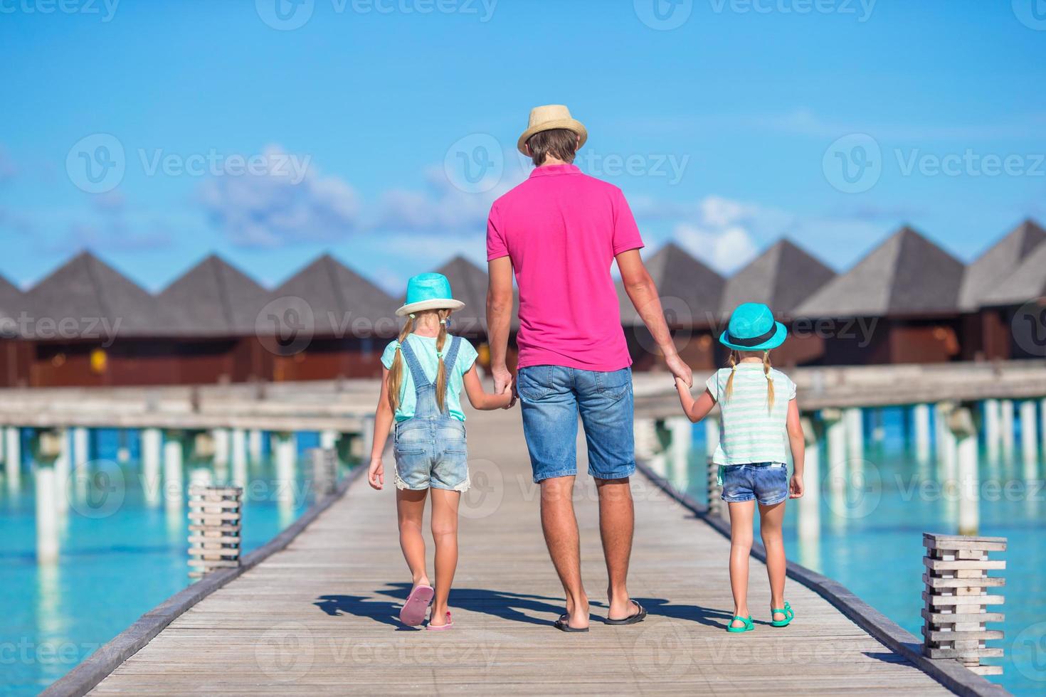 Vater und kleine Tochter auf Holzsteg in der Nähe von Wasserbungalow foto