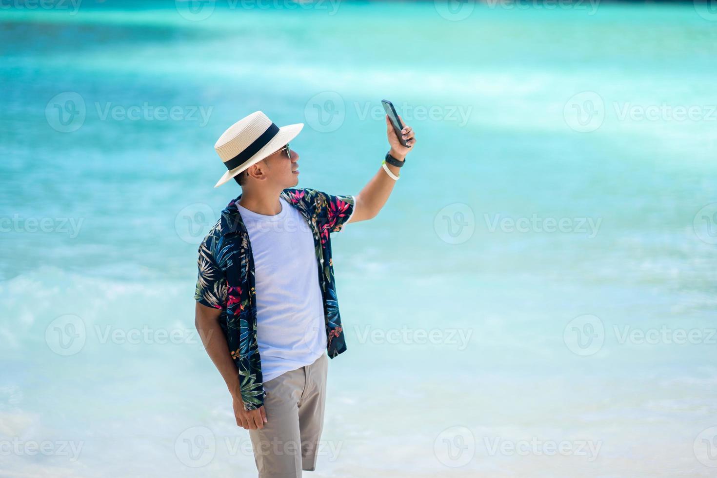 männliche touristen, die handys mitten im meer in thailand spielen foto