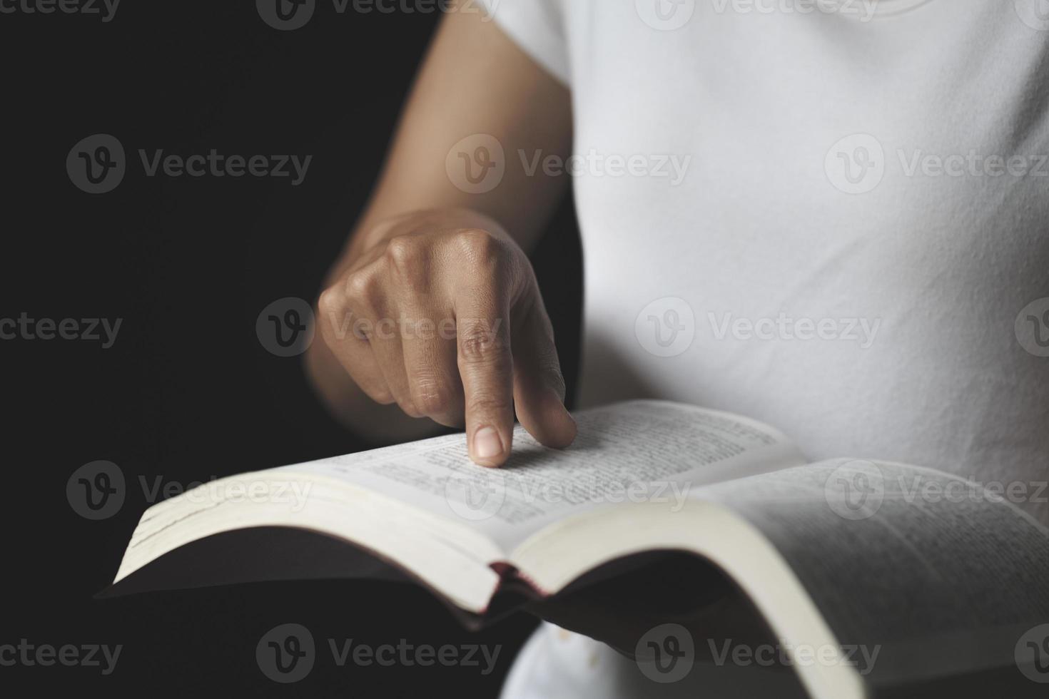 Lesen mit einer Hand, die auf die heiligen Schriften zeigt. treue und christliche frau, die ideen, glauben, glauben, gebete, wünsche betet. foto