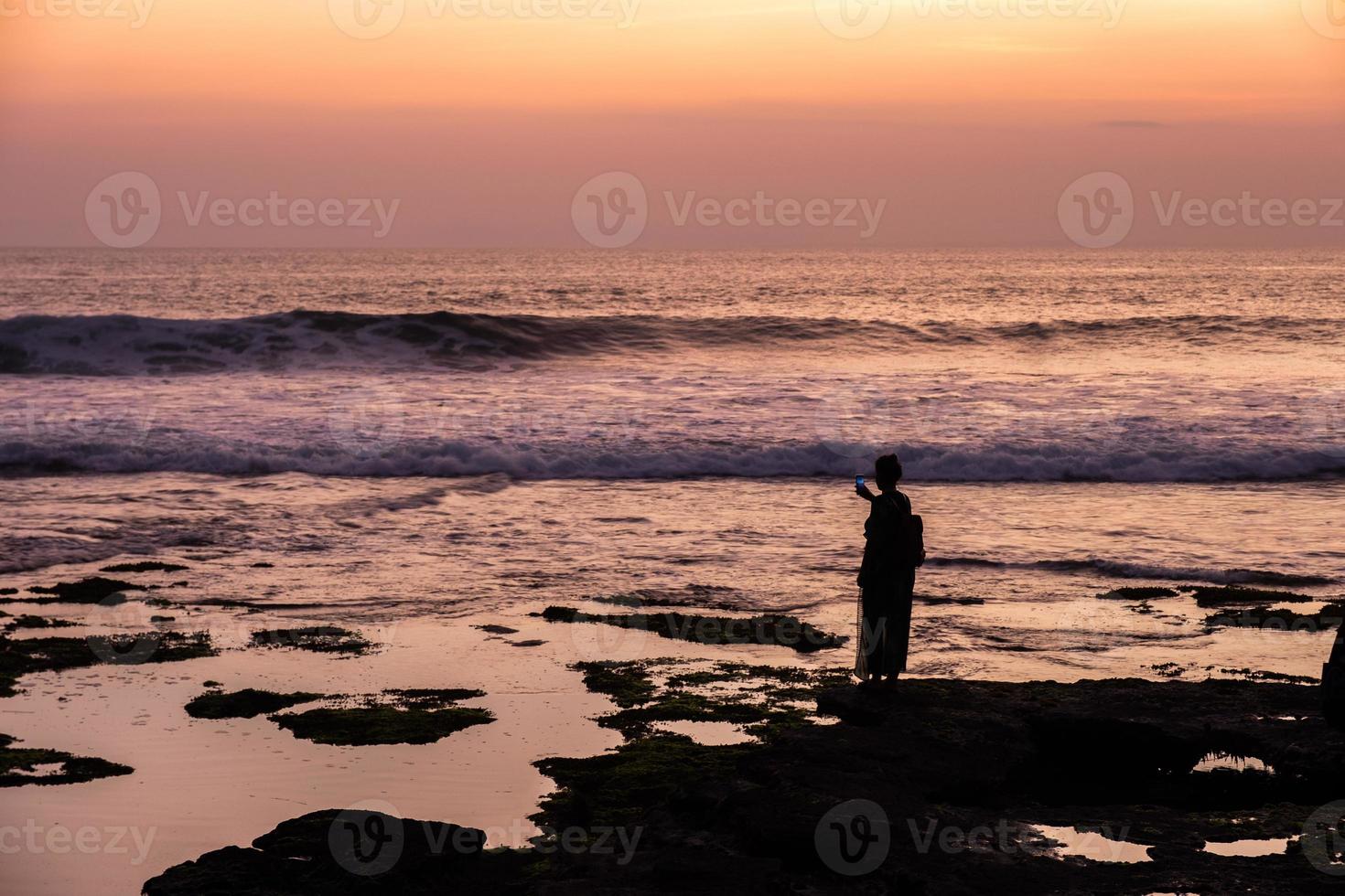 Silhouette junge Frau macht ein Foto mit wunderschönem Meer an der Küste
