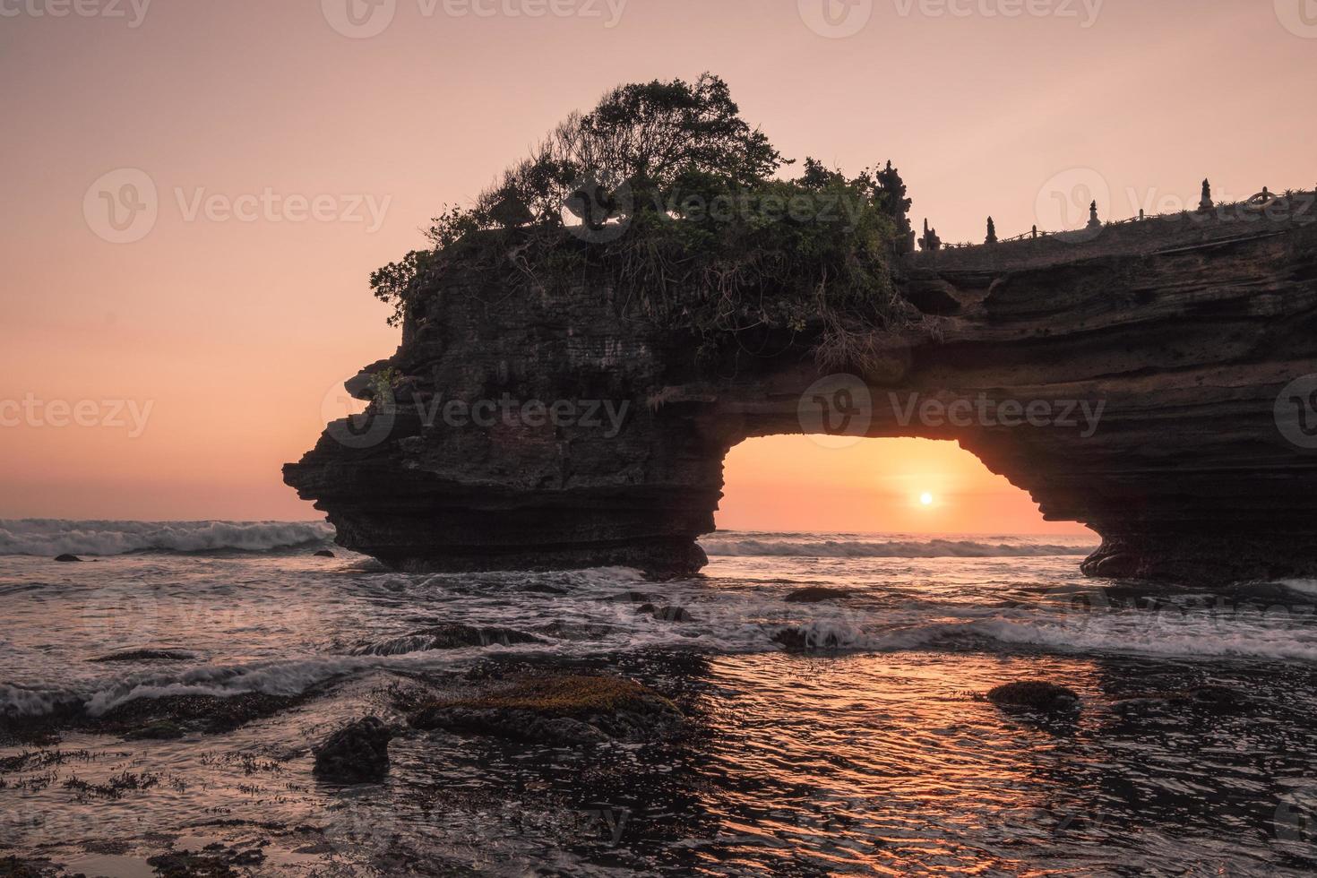 Sonnenuntergang durch die felsige Klippe am Meer bei Sonnenuntergang. pura batu bolong, bali foto