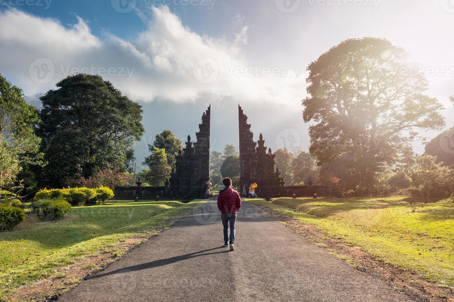 mann, der mit sonnenlicht in bali altes tor geht foto