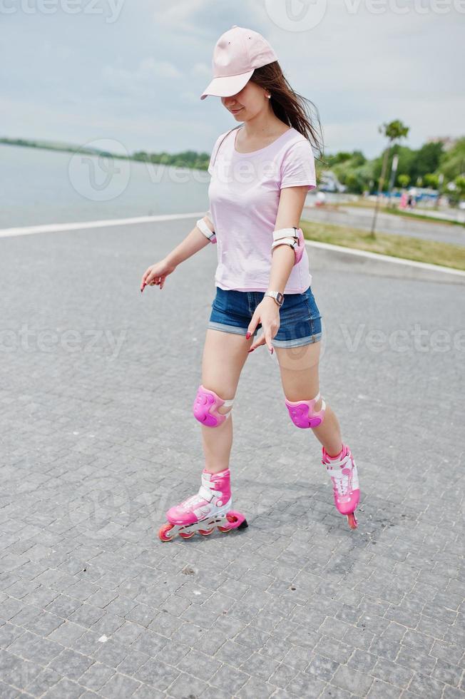 Porträt einer gut aussehenden jungen Frau in Freizeitkleidung, die auf dem Bürgersteig im Park Rollerblades fährt. foto