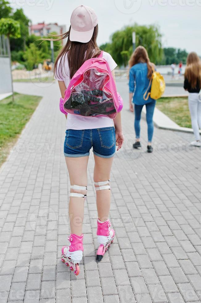 Porträt einer gut aussehenden jungen Frau in Freizeitkleidung, die auf dem Bürgersteig im Park Rollerblades fährt. foto