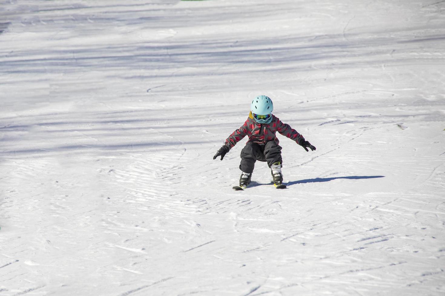 kleines Mädchen, das Skifahren auf einer Skipiste lernt foto