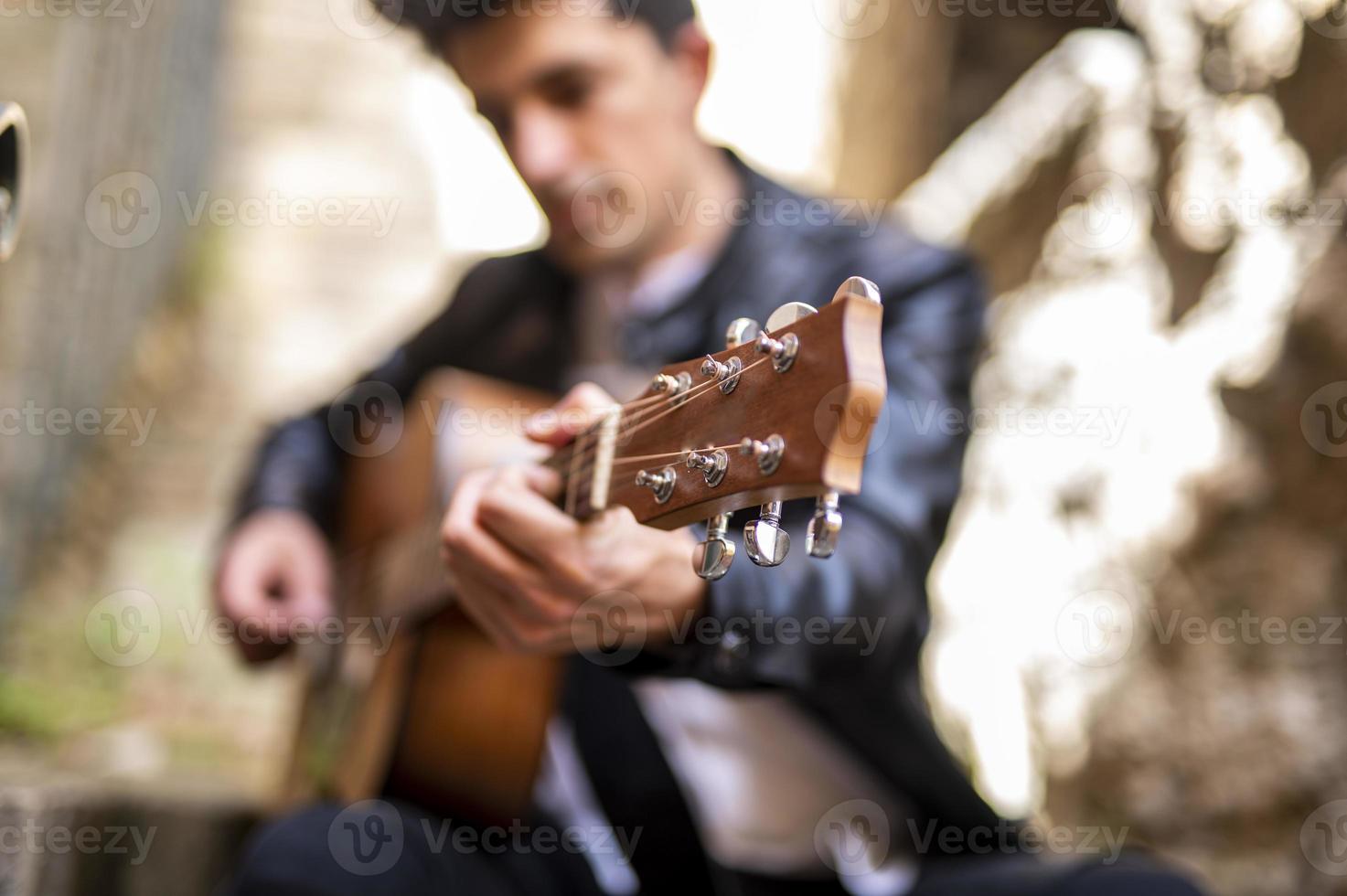 Fokusdetail eines Jungen, der Gitarre spielt foto