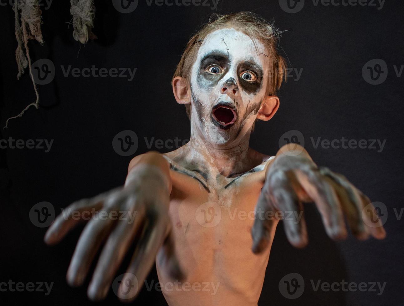 Studioaufnahme Porträt eines kleinen Jungen in Kostümen, die als Halloween verkleidet sind, Cosplay einer gruseligen Mumienpose auf isoliertem schwarzem Hintergrund foto