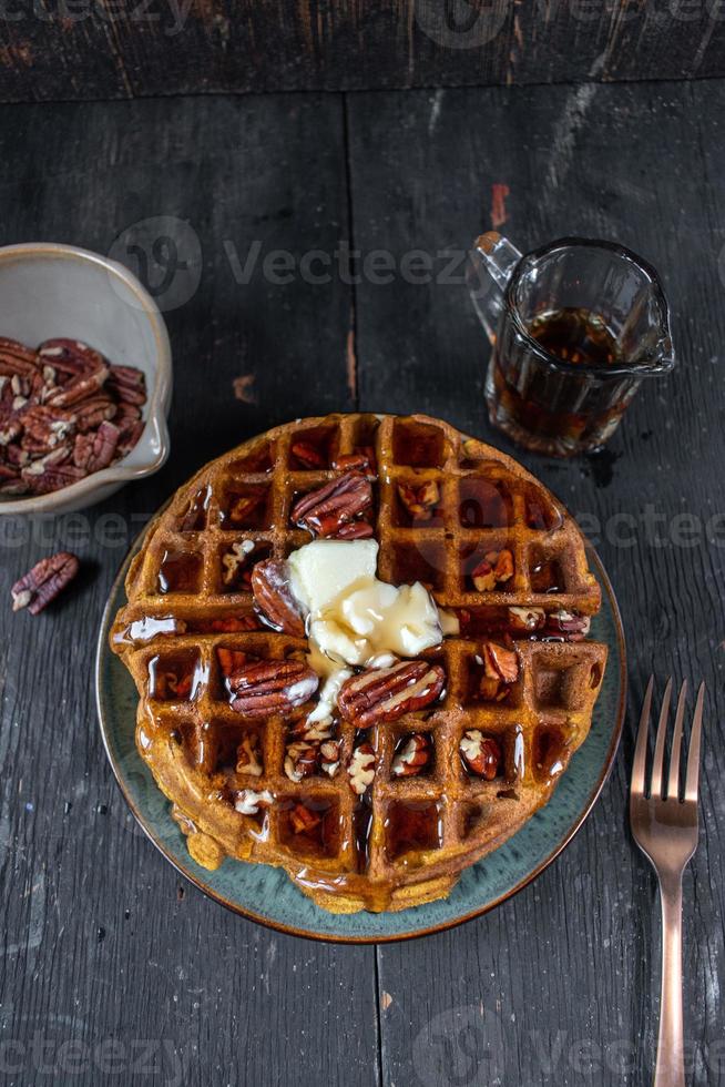 Kürbiswaffeln mit Pekannüssen, garniert mit Butter und Sirup, flach gelegt foto