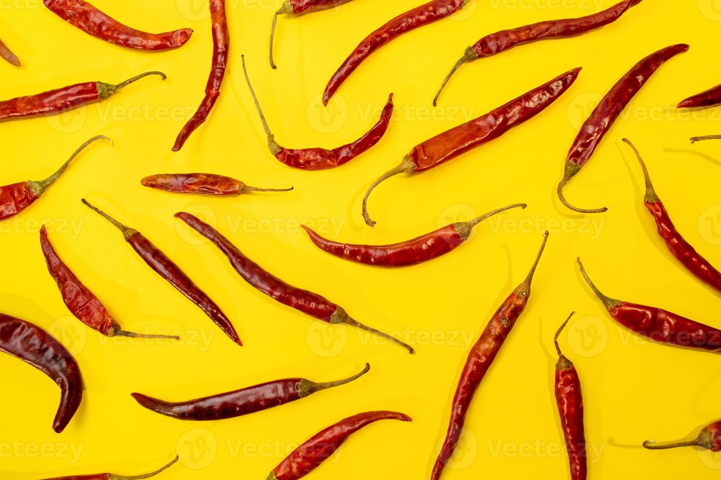 rote chile de arbol chilis, die als muster auf einem lebhaften gelben hintergrund ausgelegt sind foto