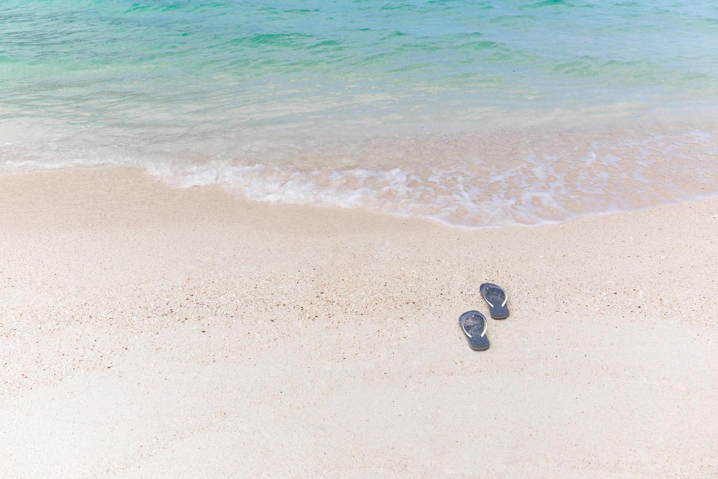 tropisches Urlaubskonzept Flip-Flops an einem Sandstrand. foto