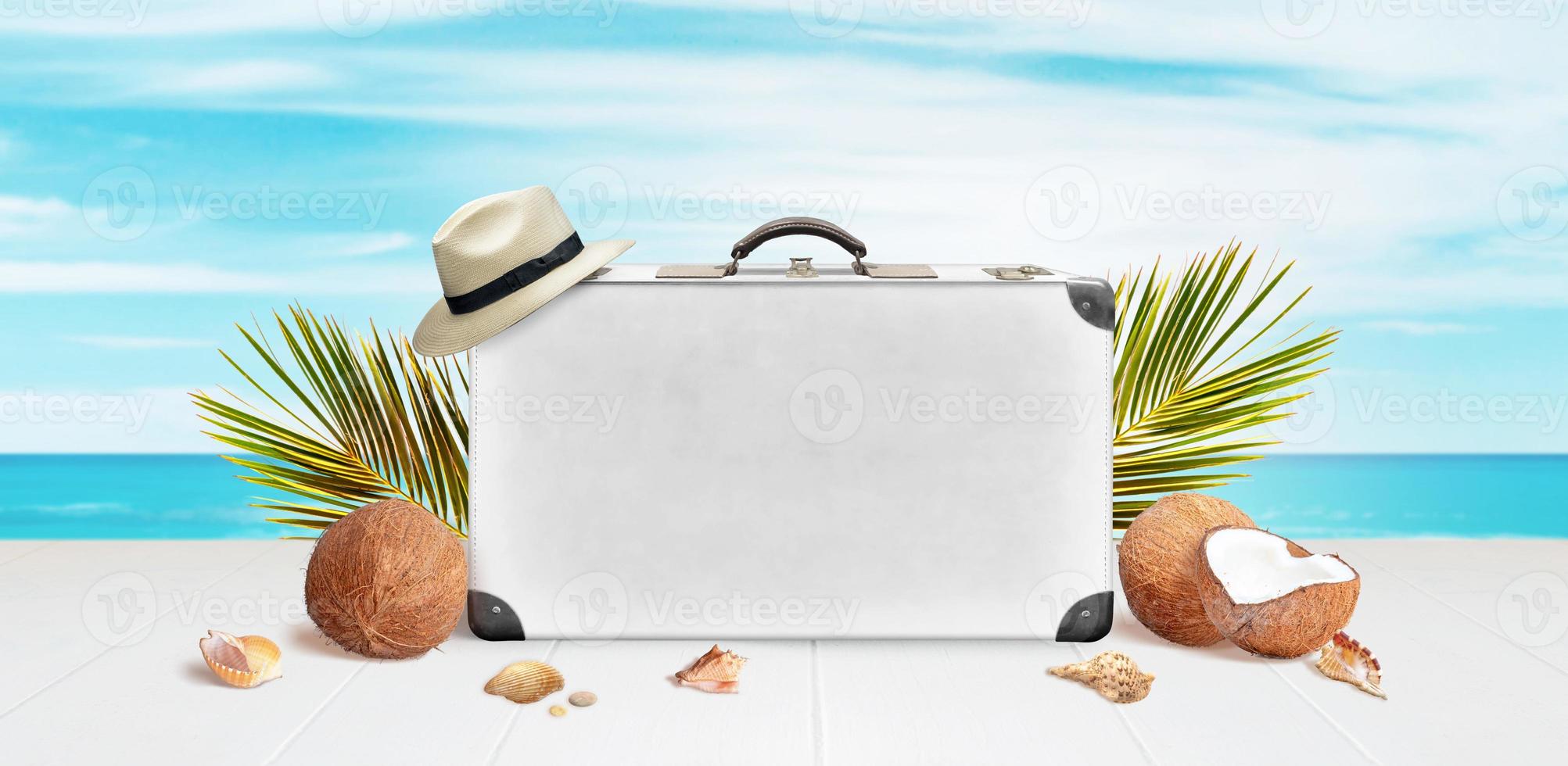 weißer Koffer mit Platz für Text- oder Logopräsentation, umgeben von Palmblättern, Kokosnüssen und Muscheln. Sommerreisekonzept foto