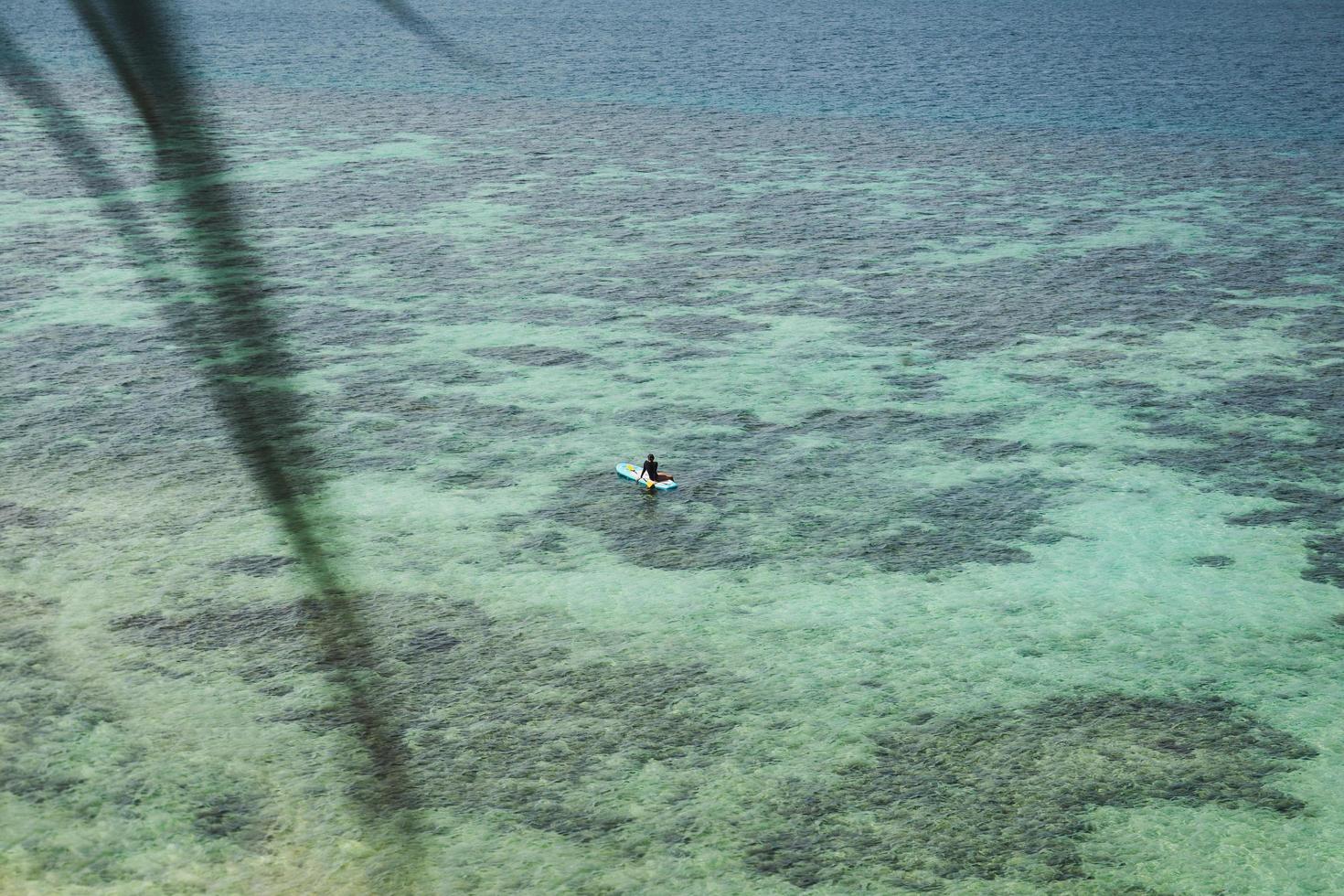 Frau, die sich auf dem Stand Up Paddle Board am blauen Meer entspannt. foto