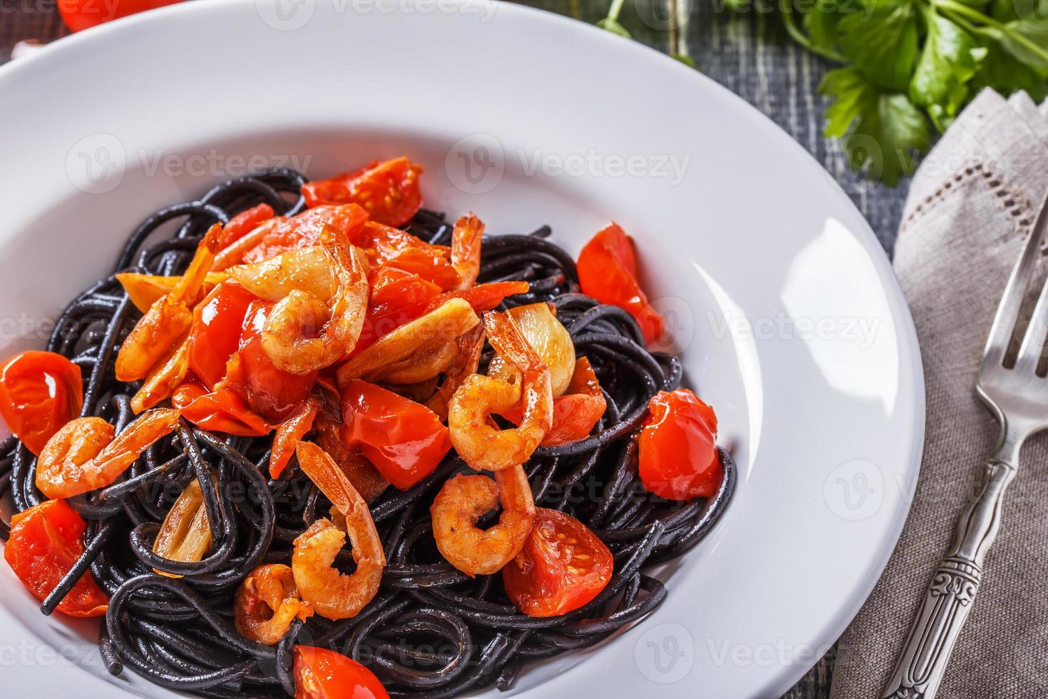 schwarze Spaghetti mit Garnelen und Tomaten. foto