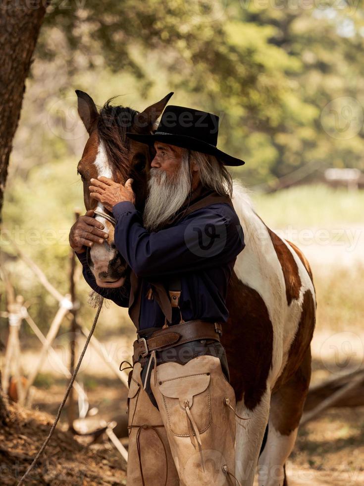 Cowboy berührt das Pferd mit Liebe foto