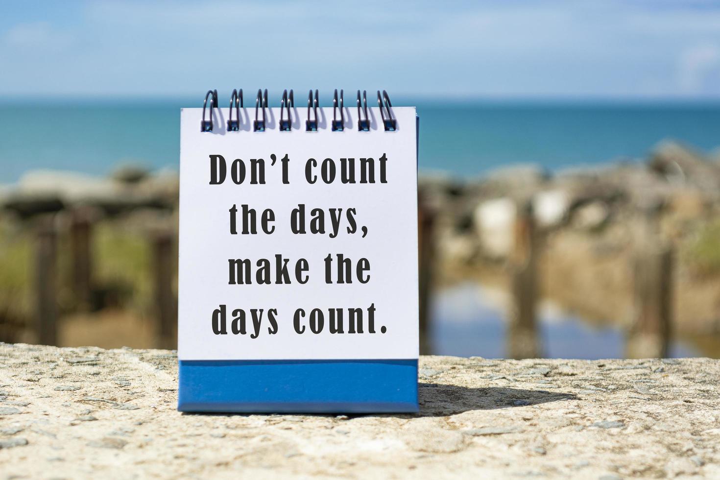 motivierendes und inspirierendes Zitat auf einem Notizblock mit verschwommenem Strandhintergrund foto